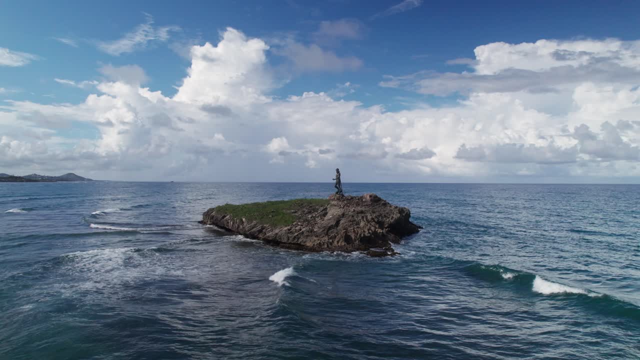 Drone-tilbagetrækningsskud, der starter fra et nærbillede af Neptun-statuen og udvider sig til en bred udsigt over den klippefyldte holm og Atlanterhavet. Et filmisk kystlandemærke i Den Dominikanske Republik.