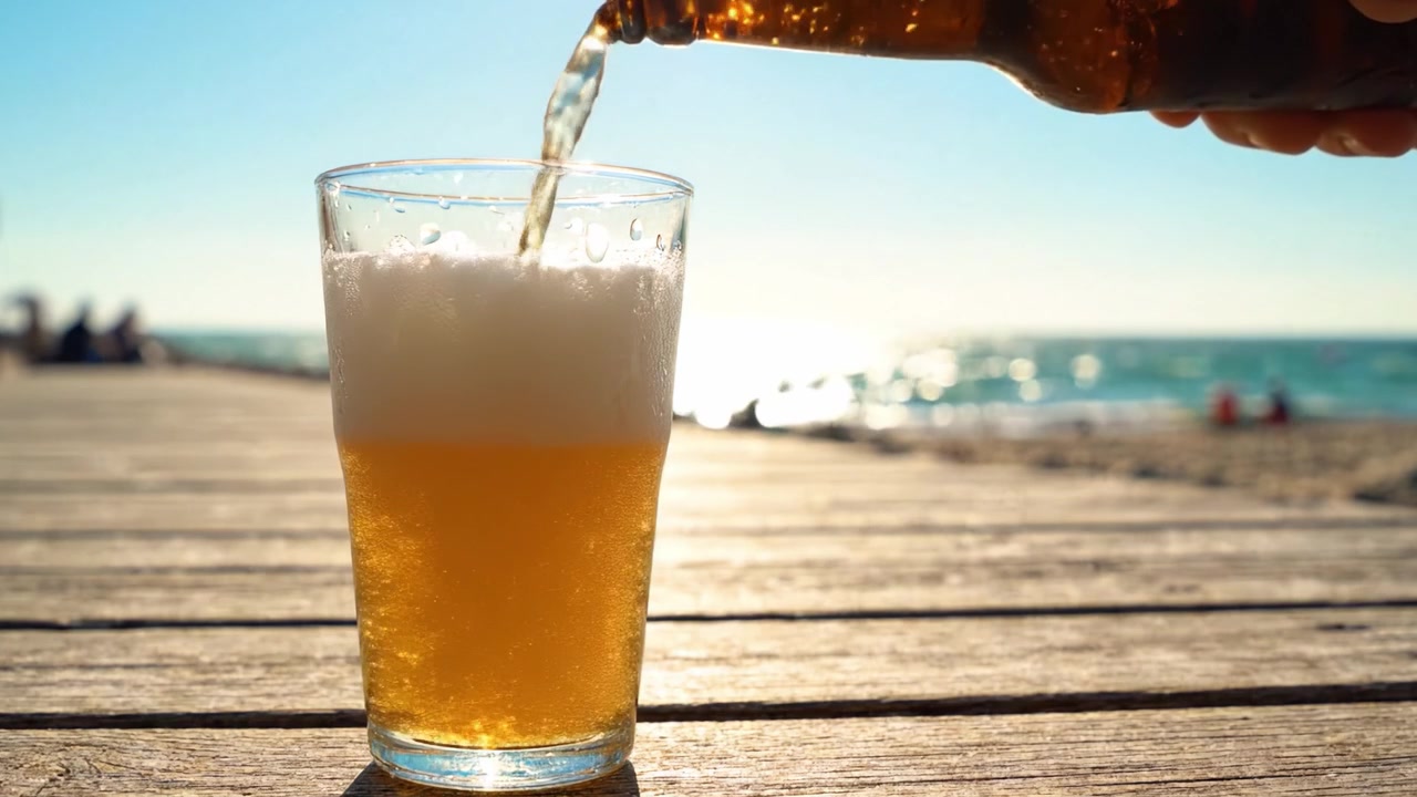 Birra rinfrescante versata sulla spiaggia: una scena accattivante di birra dorata e sole con una perfetta combinazione di natura e relax.