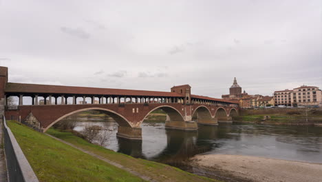 ponte coperto is a bridge over the ticino river in pavia, pavia cathedral background, time lapse at cloudy day