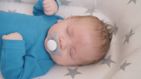 newborn baby with pacifier sleeps in cocoon in rocking crib