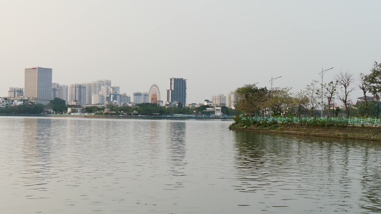 el agua del lago tay ho refleja los edificios de la ciudad y la naturaleza de la costa