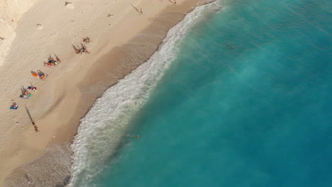 Turistas-Tomando-El-Sol-En-La-Orilla-Arenosa-De-La-Playa-De-Porto-Katsiki-En-La-Isla-De-Lefkada,-Grecia