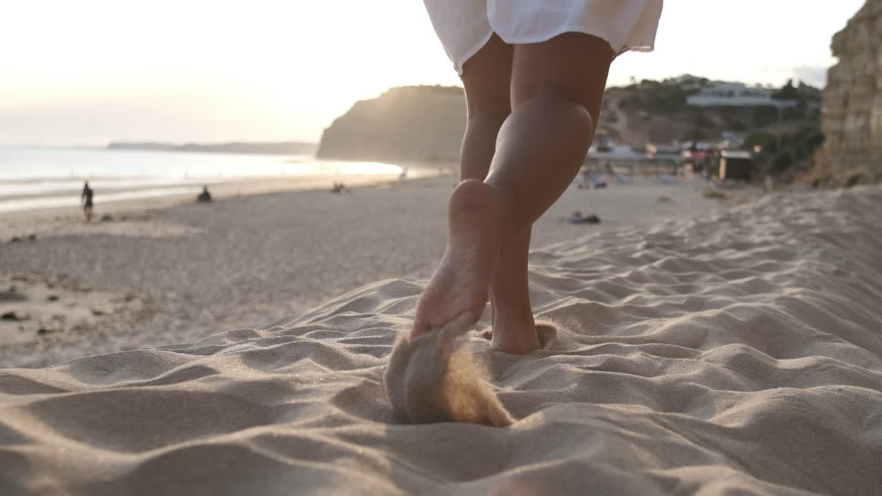 Unrecognizable woman running in the summer sunset along the sunny exotic shore in Portugal. Slow motion, low angle, close-up