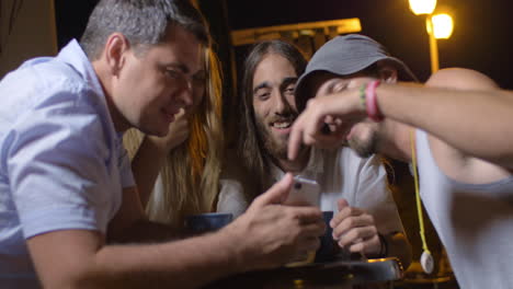 Amigos-Viendo-Algo-En-El-Teléfono-Inteligente-Y-Riéndose-Del-Par