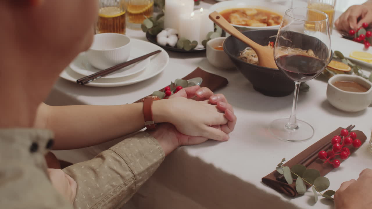 Couple Holding Hands while Dining with Family