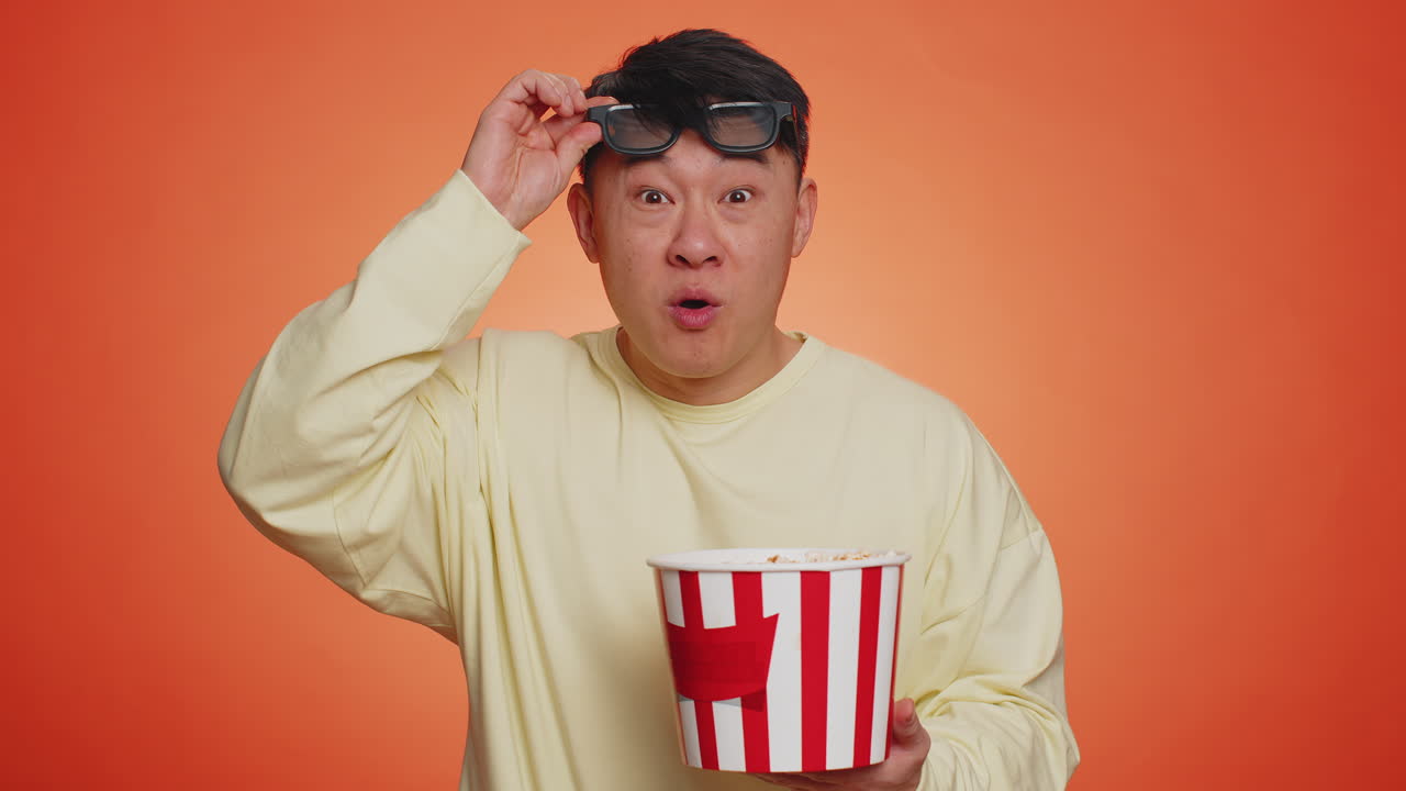 Excited man in 3d glasses eating popcorn and watching interesting tv serial sport game film movie