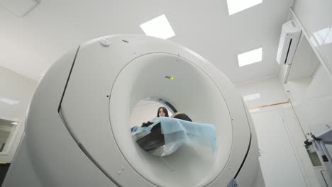 la paciente está siendo sometida a una tomografía computarizada o resonancia magnética bajo la supervisión de un radiólogo en una clínica médica moderna. la paciente está acostada en una cama de tomografía computorizada o resonanza magnética, moviéndose dentro de la máquina.