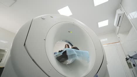 female patient is undergoing ct or mri scan under supervision of a radiologist in modern medical clinic. patient lying on a ct or mri scan bed, moving inside the machine.