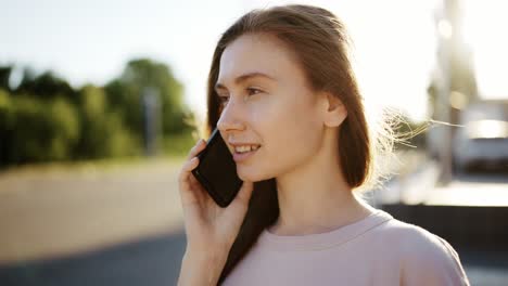 Mujer-Feliz-Hablando-Por-Teléfono-Móvil-Al-Aire-Libre,-Destellos-De-Lente-En-El-Fondo