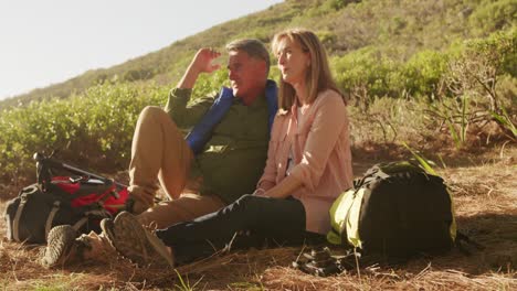 active senior couple sitting on the floor in forest