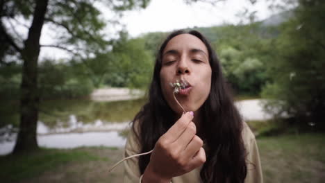 Lovely-mixed-race-woman-blows-and-disperse-seeds-of-a-dandelion