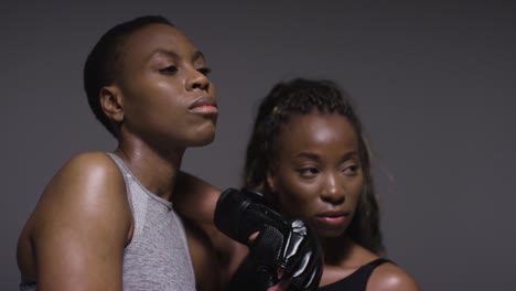 Studio-Portrait-Shot-Of-Woman-Wearing-Boxing-Gloves-Sparring-With-Trainer-4