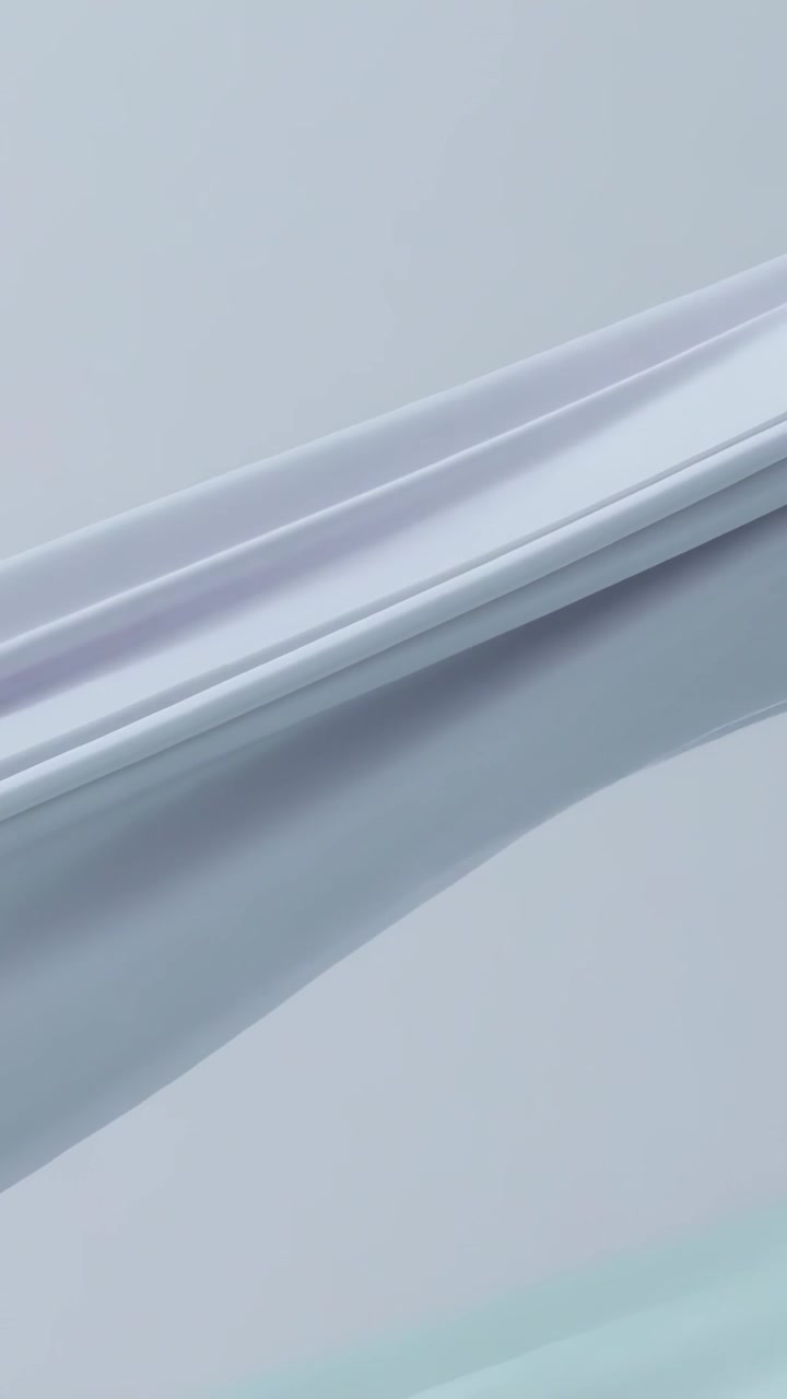 Vertical video: Subtle motion starting glossy ribbons sliding at pale backdrop showing teal sheen