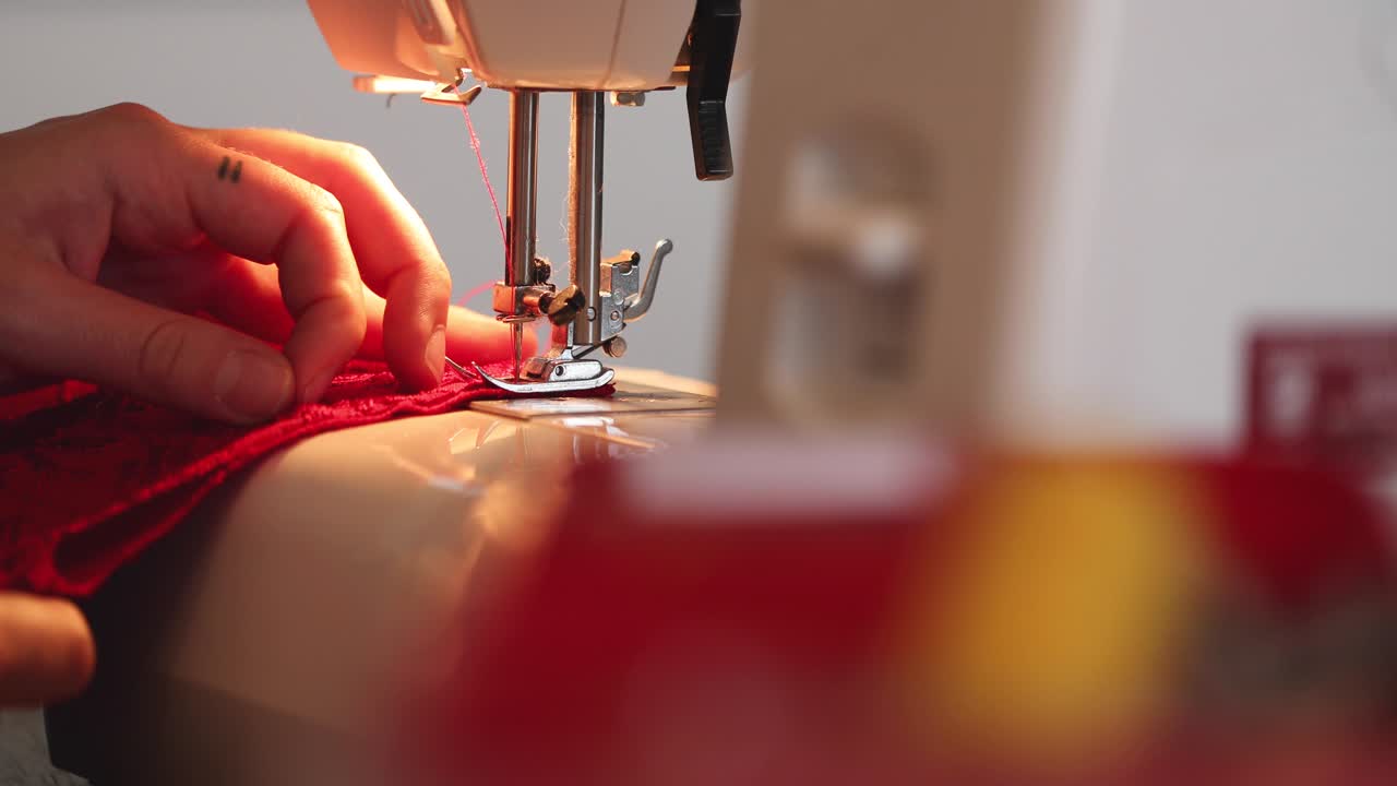 manos femeninas usan máquina de coser en vestido rojo en 4k