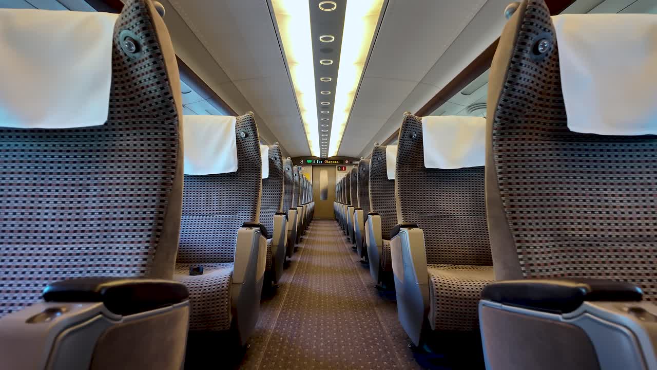 Empty passenger seats with white headrest covers inside a green car of a Shinkansen bullet train in Japan