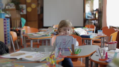 mädchen zieht am tisch im klassenzimmer. bildung. kind sitzt an einem schreibtisch