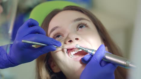 female patient on teeth cleaning procedure. dentist hands working