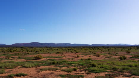 Low-aerial-drone-shot-of-a-semiarid-vast-landscape-with-a-mountain-range-in-the-background