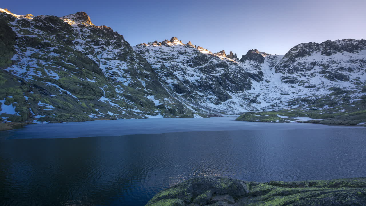 puesta de sol en la laguna grande de gredos, reflejo perfecto de las montañas en el lago medio congelado
