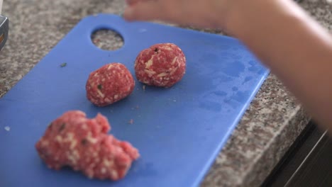 Woman-making-meatballs-in-a-blue-table-and-making-a-round-form-with-her-hands-at-24fps-full-hd