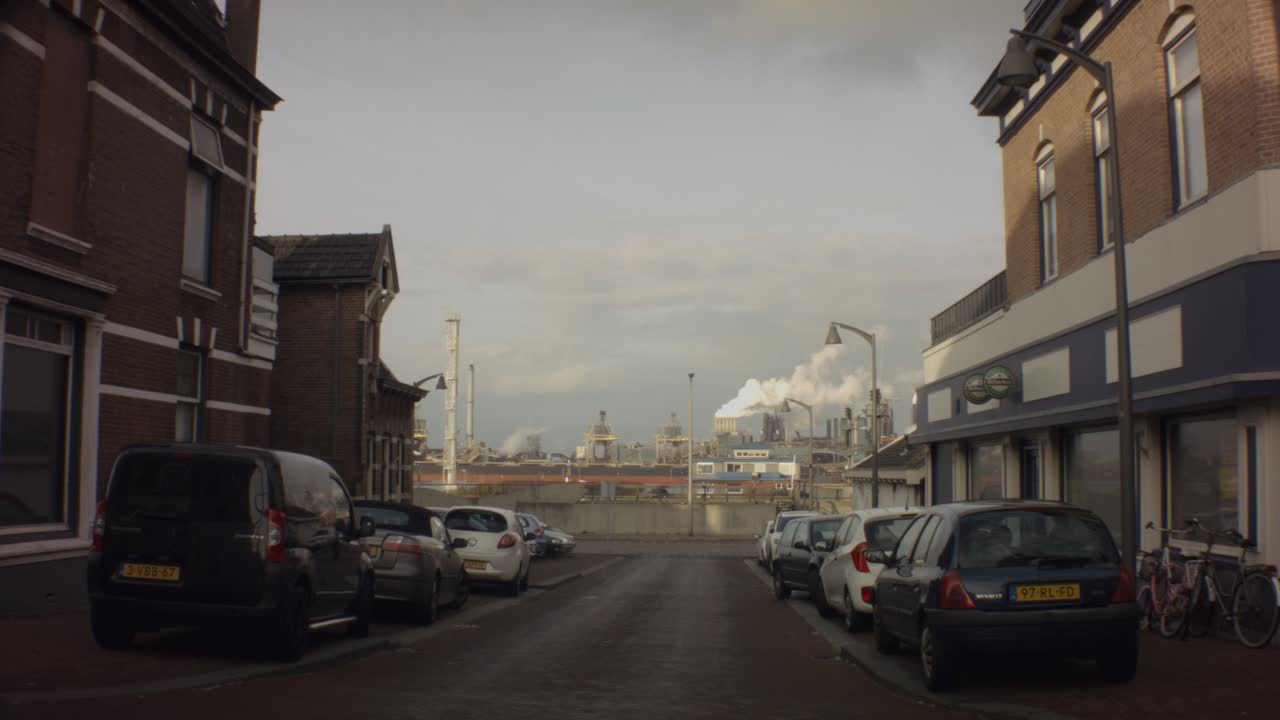 Old Ijmuiden - Netherland - January 21st 2019 : still view of street Visseringstraat across Sluisplein in harbor during winter with cityscape of Tata steel steel factory plant