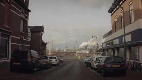 old ijmuiden - netherland - january 21st 2019 : still view of street visseringstraat across sluisplein in harbor during winter with cityscape of tata steel steel factory plant
