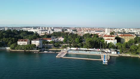 Panorama-Más-Amplio-Zadar-Aéreo-Costero-Sobre-Piscina-Marina-Con-Plataforma-De-Buceo-Y-Ciudad-En-El-Fondo