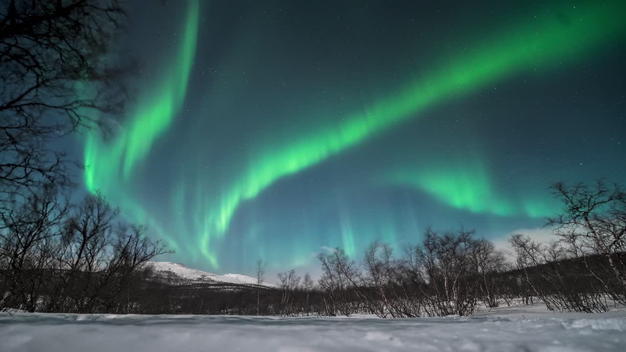 Dancing green aurora over snowy Kilpisjärvi landscape, stunning winter night timelapse