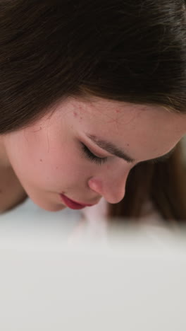 woman sits at table in public library closeup. brunette lady reads book at desk in light hall of literature storage. pretty student learns information