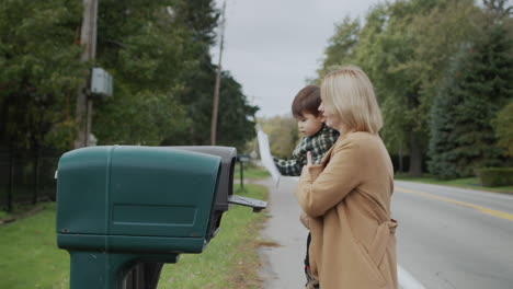 a woman with a child goes to the mailbox to send a letter.