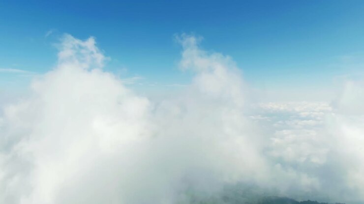 Drone video captures an awe-inspiring aerial view of fluffy clouds against a clear blue sky, providing a stunning perspective from above with serene and expansive atmosphere