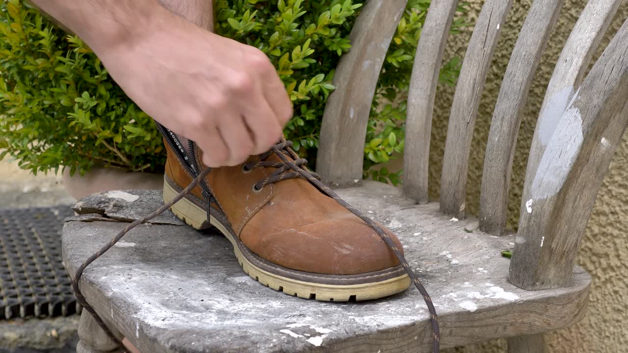 Saving a pair of laces from an old brown boot to recycle and reuse them, highlighting sustainable practices in everyday life