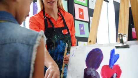 maestra ayudando a una estudiante en la clase de dibujo
