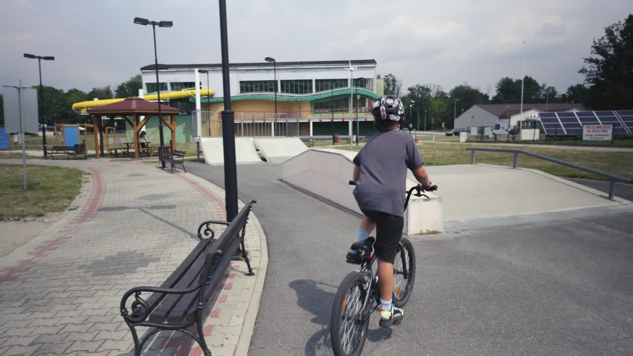 스케이트 파크를 가로질러 bmx 자전거를 타고 있는 헬 ⁇ 을 입은 소년