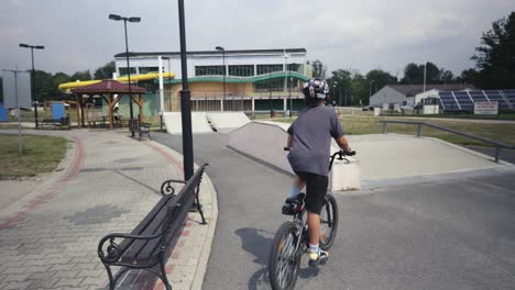 스케이트 파크를 가로질러 bmx 자전거를 타고 있는 헬 ⁇ 을 입은 소년