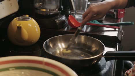 Swirling-Sliced-Butter-To-Melt-In-A-Low-Heated-Frying-Pan---Close-Up-Shot