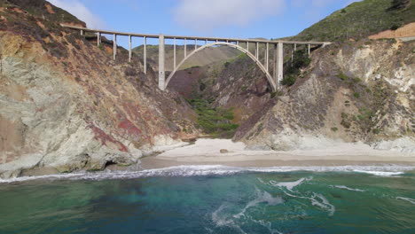 Aerial-Flying-Towards-Bixby-Bridge-Over-Ocean-Waves-At-Big-Sur