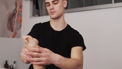 Close-up-portrait-of-a-male-massage-therapist-giving-a-gentle-foot-massage-to-a-woman