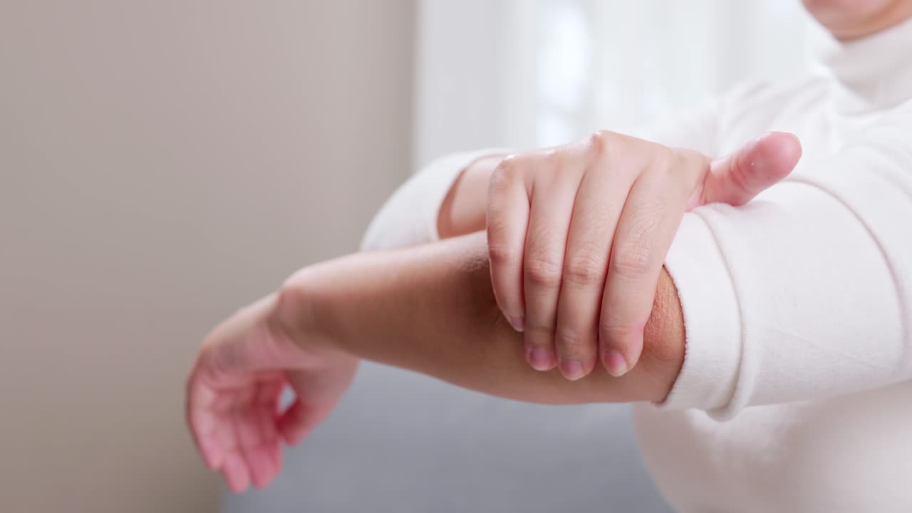 женщина с болью в локте использует руки для массажа, чтобы облегчить боль и помочь симптомам улучшиться