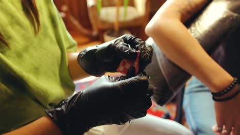 hands of female tattoo artist preparing needle for tattooing