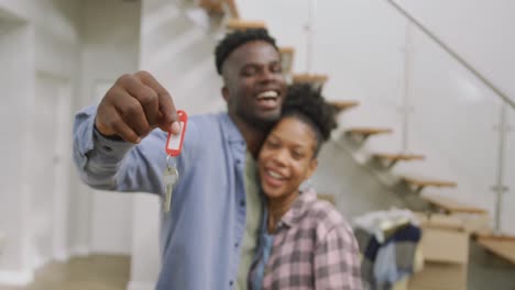 Video-of-happy-african-american-couple-embracing,-showing-keys-to-new-house