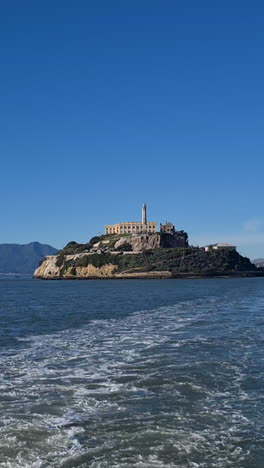 vertical view, sailing away from alcatraz prison island on sunny day, san francisco bay, california usa