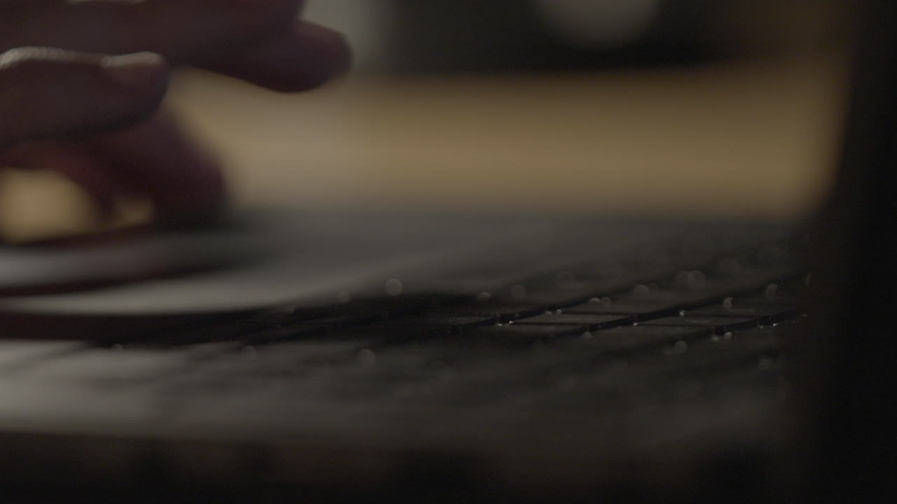 primer plano de las manos escribiendo en un teclado de portátil por la noche