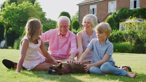 grandparents and pre-teen grandkids petting dog in garden