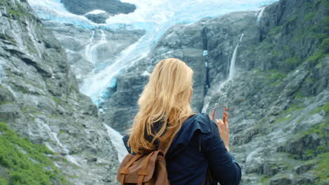 woman taking picture of glacier in norway