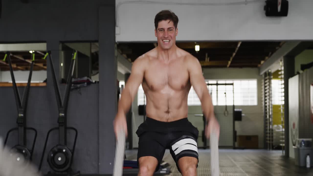 vista frontal hombre atlético caucásico trabajando con cuerdas de batalla