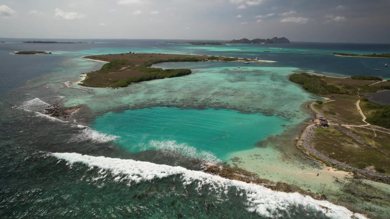 De turquoise natuurlijke poel van het eiland Madrisquí met omringend groen en blauw water, luchtfoto