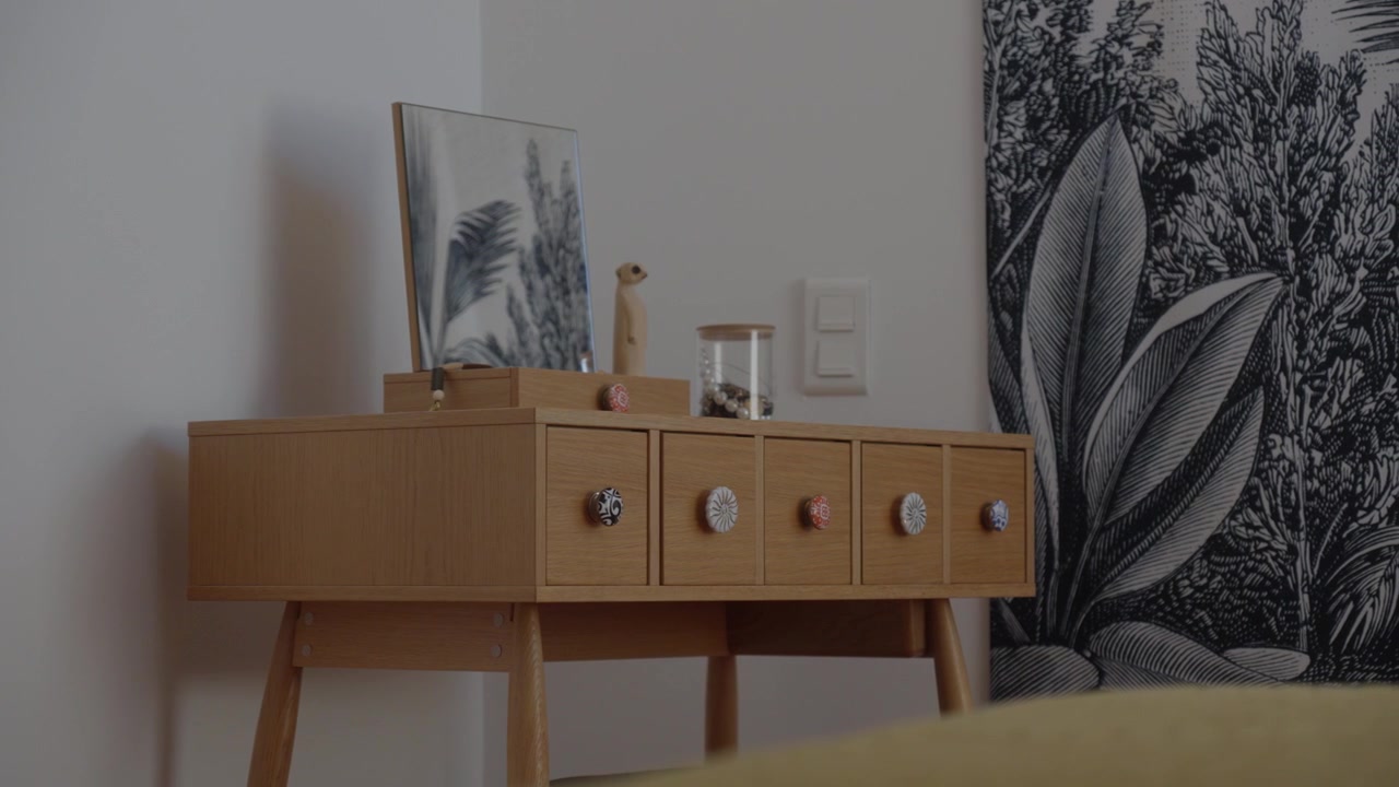 Mid-century style dresser with decorated knobs in a cozy bedroom corner, daylight scene