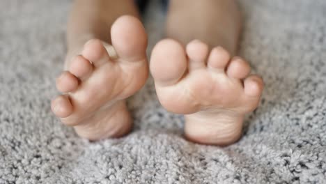 누군가 발가락을 쭉 뻗은 보송보송한 밝은 회색 담요 위에 누워 있을 때 고양이가 다가와 냄새를 맡는 동안 두 발의 발바닥
