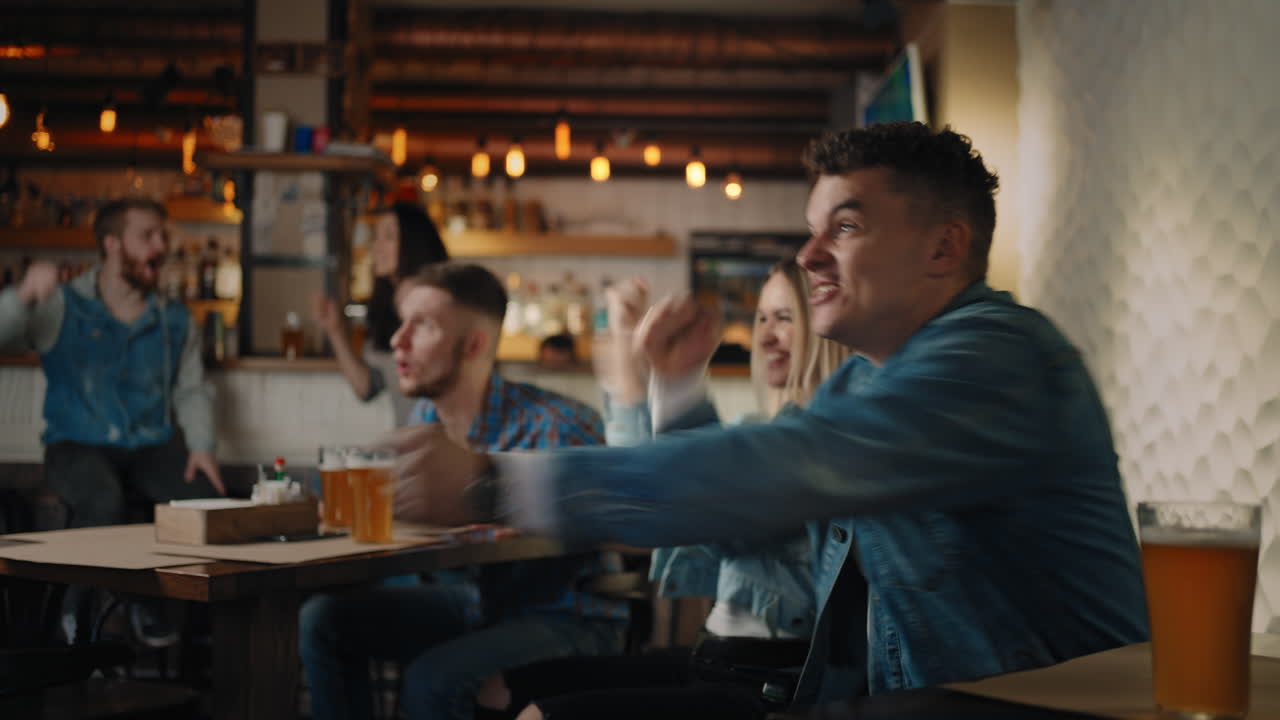 Friends are watching together emotionally watching football on TV in a bar and celebrating the victory of their team after scoring a goal. Watch basketball hockey. Fans in the pub